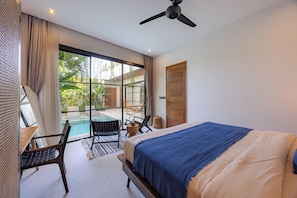 A bedroom with a bed, a ceiling fan, a view of an outdoor pool, and a wooden door. - 2BR Private Pool Villa with Rice Field Views & Sunset Balconies (Badung)