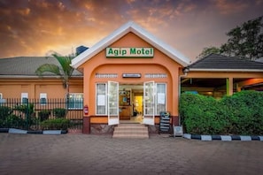 Das Äußere des Agip Motel mit einer Rezeption, einem eingezäunten Bereich und einem gepflasterten Eingang.