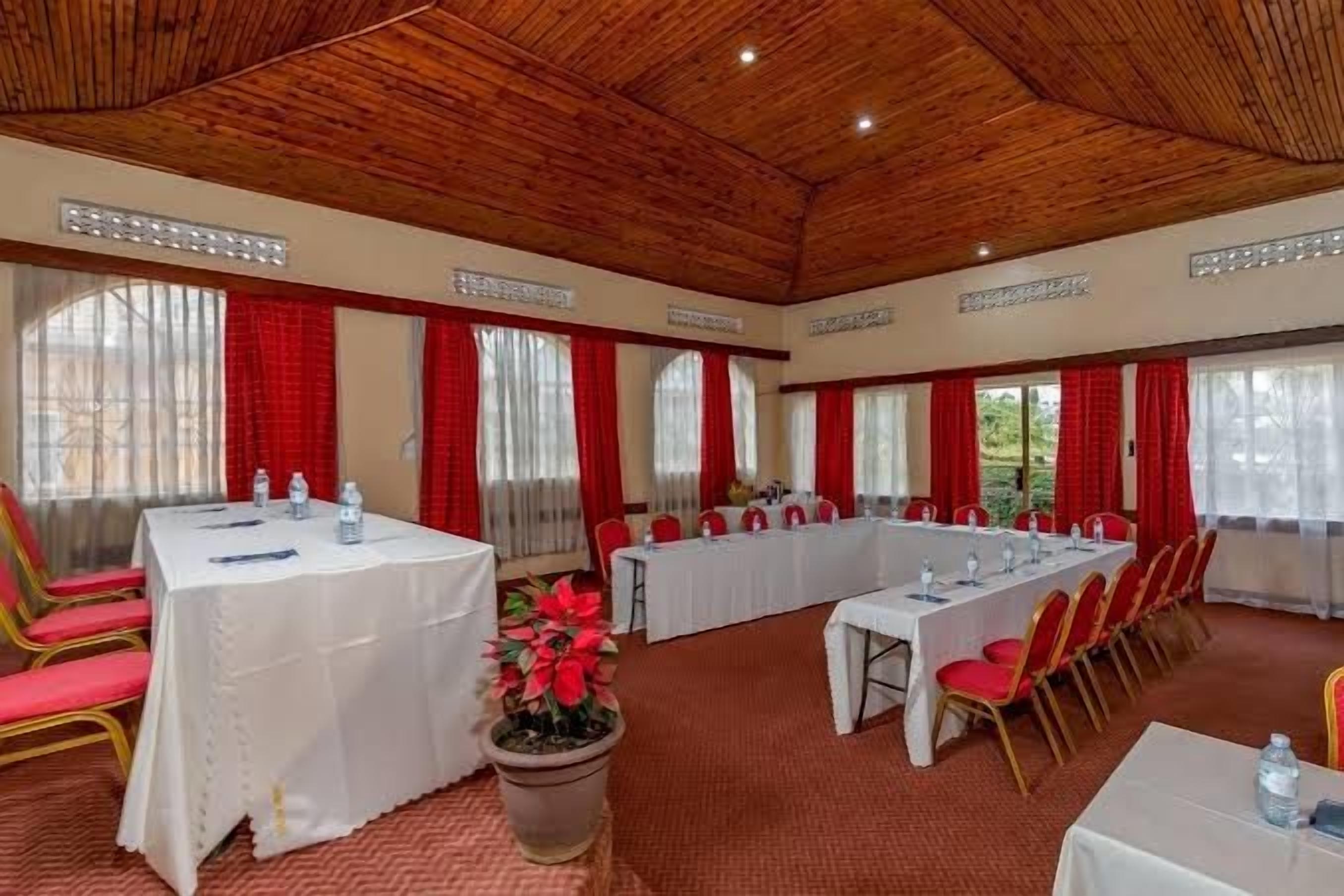 Uma sala de conferência com uma mesa comprida, cadeiras e um vaso de planta.