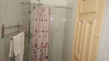 A shower area with a glass door, a towel rack, and a shower curtain.