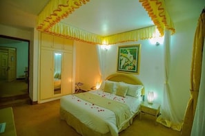 A bedroom with a bed, bedside table, and a mirror. - Agip Motel Mbarara (Mbarara)