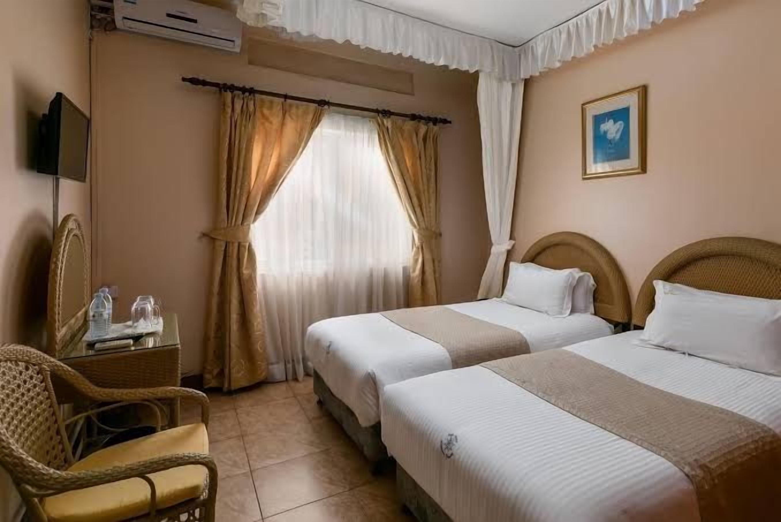 Una habitación de hotel con dos camas, una silla, un escritorio y un televisor.