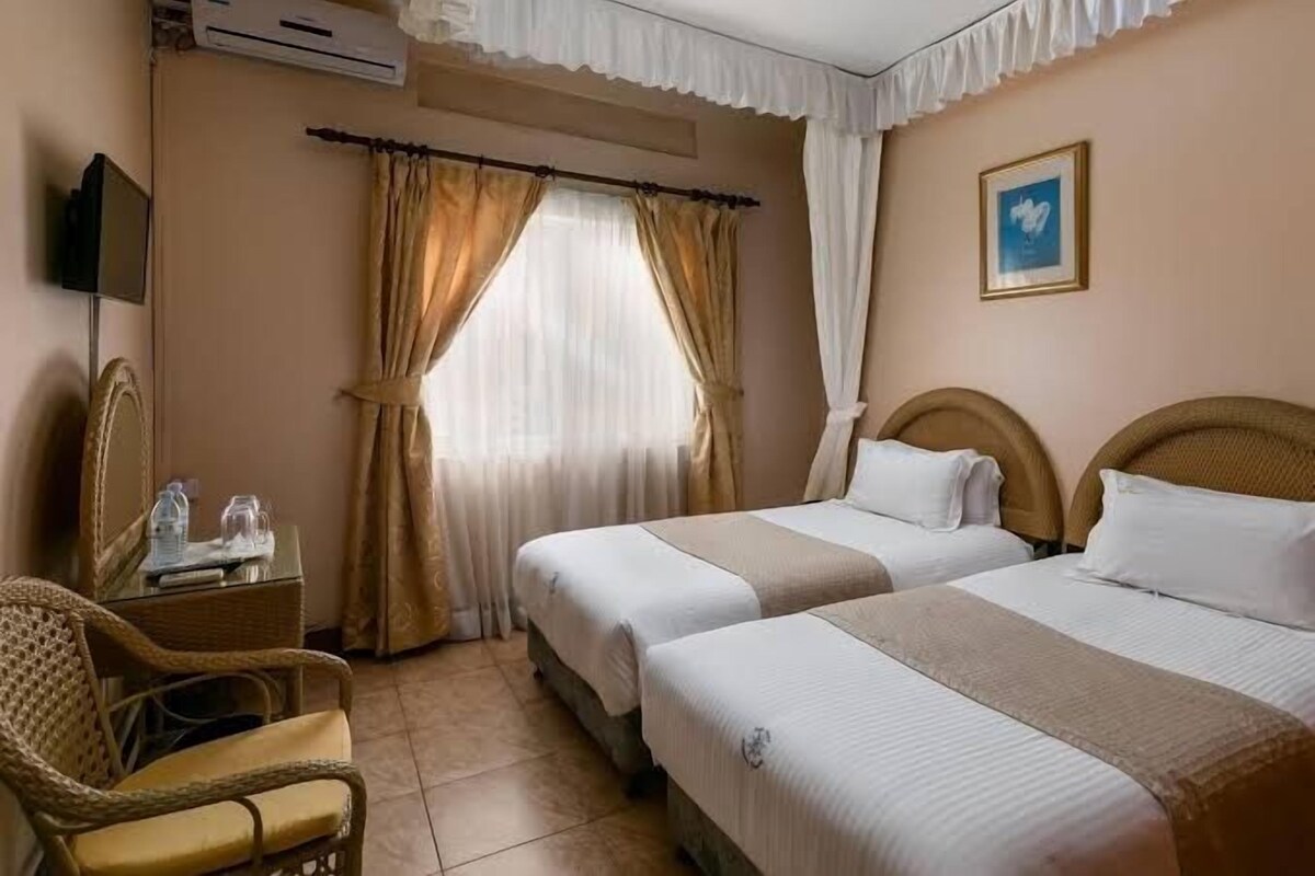 Una habitación de hotel con dos camas, una silla, un escritorio y un televisor.