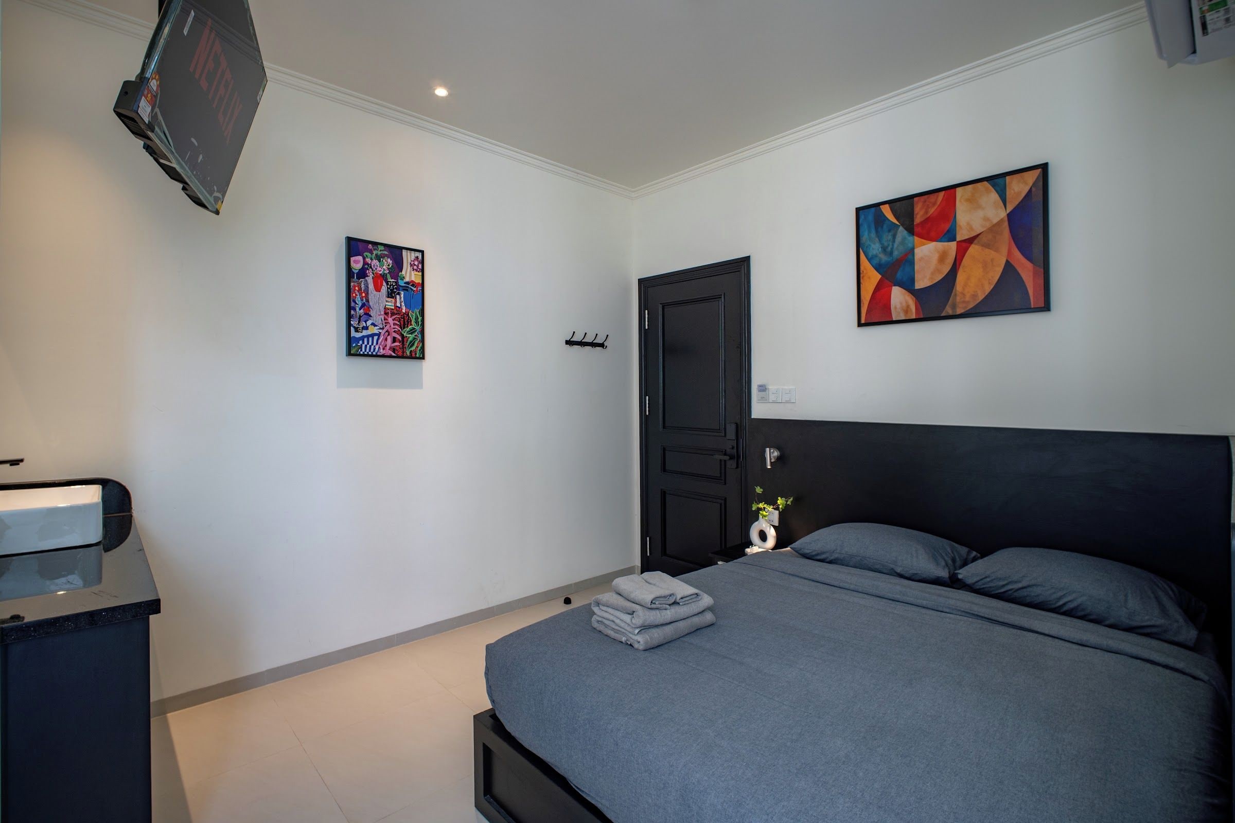 Ein modernes Schlafzimmer mit Bett, Fernseher und Kunstwerken an den Wänden.