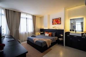 Una camera d'albergo moderna con un letto grande, una scrivania, una lampada da scrivania, un comodino, uno specchio e una finestra con tende.