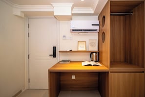 A compact room with a wooden desk, a bookshelf, a framed artwork, and a coffee maker. - le Jardin Lite Ban Co (Ban Co)