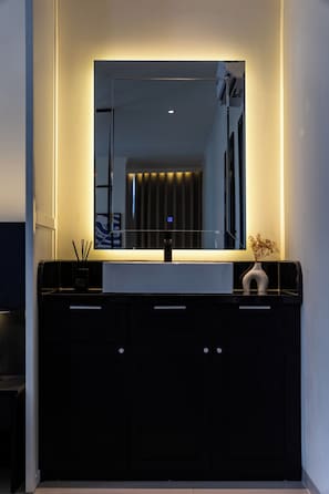 Un bagno moderno con uno specchio grande, un mobile lavabo nero e una piccola pianta sul ripiano.