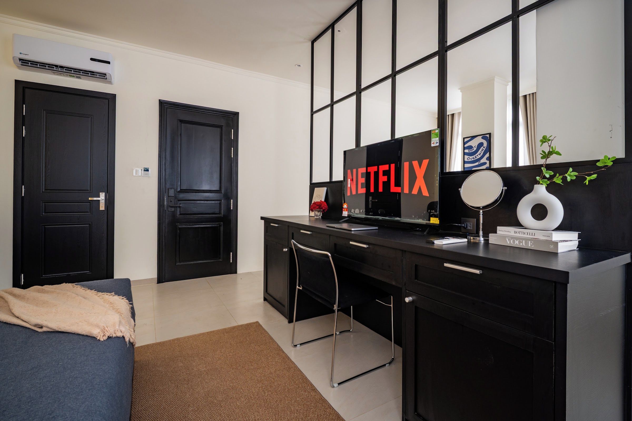 Une chambre moderne avec un bureau noir, un grand téléviseur à écran plat et une bibliothèque.