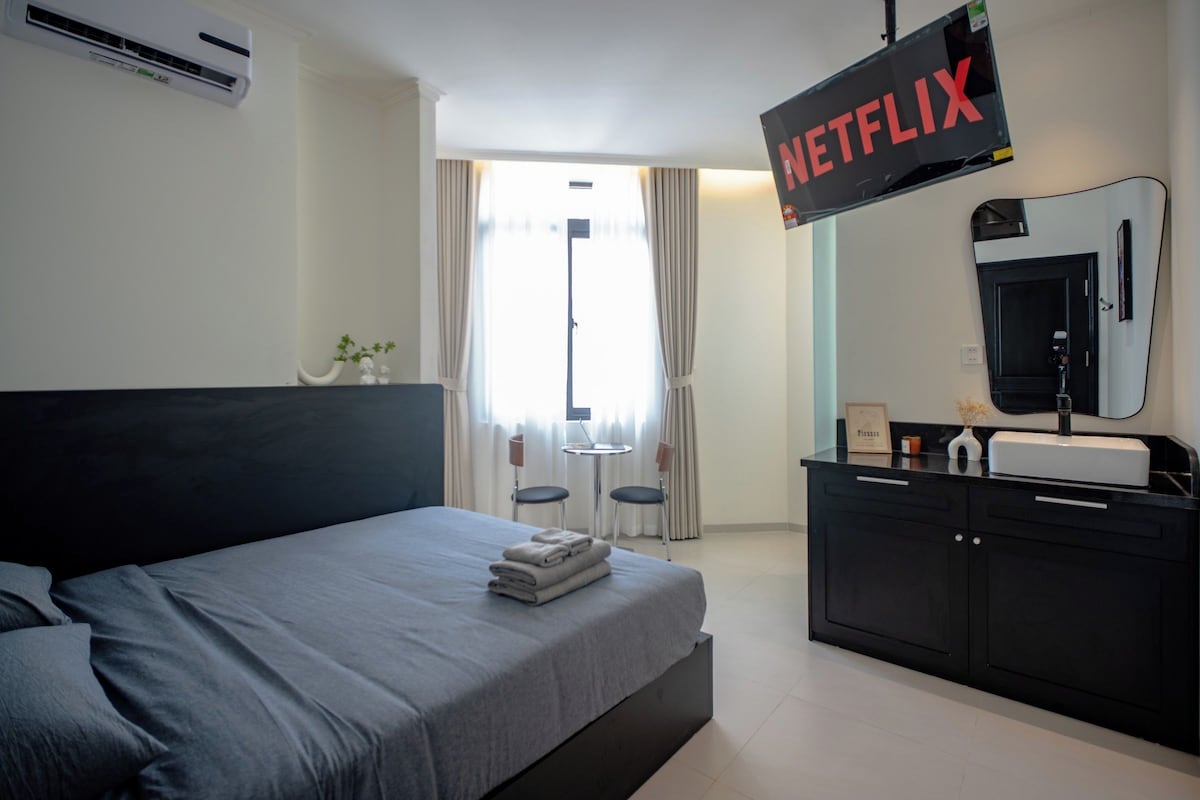 Una camera d'hotel con un letto, una scrivania, uno specchio e una TV a muro.