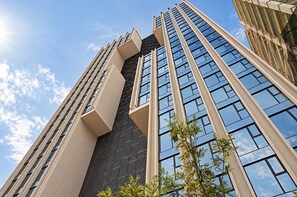 Un edificio de gran altura con un diseño arquitectónico moderno, que destaca por una fachada prominente con grandes ventanales y un diseño geométrico.