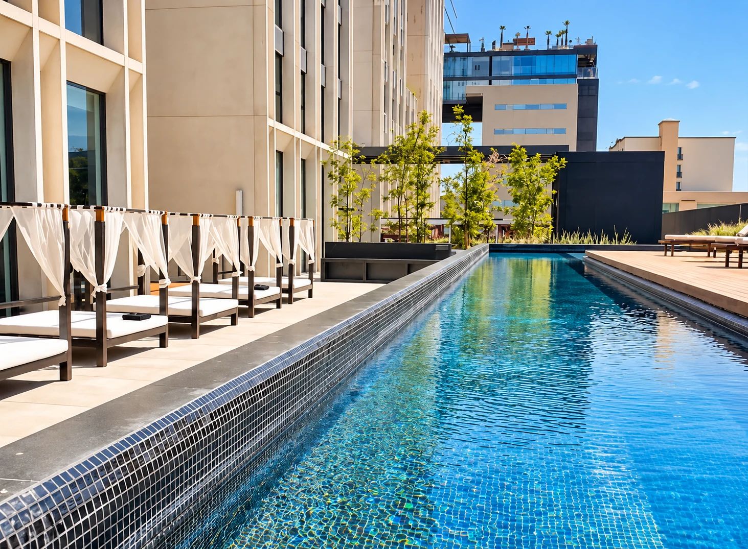 A swimming pool with a tiled edge, adjacent to a building with multiple floors and balconies.