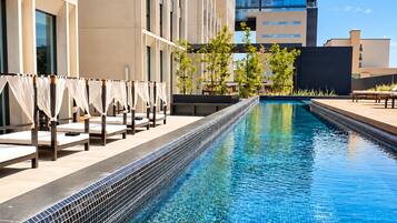 A swimming pool with a tiled edge, adjacent to a building with multiple floors and balconies.