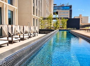 A swimming pool with a tiled edge, adjacent to a building with multiple floors and balconies. - APT21 Puebla - Volcano, Ferris Wheel & City Views in Torres Boudica (San Andrés Cholula,)