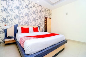 Una habitación de hotel con cama, mesita de noche, pared con diseño de bambú y una puerta.