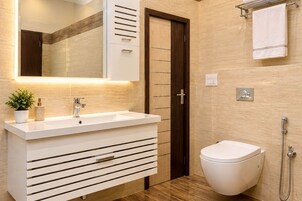 A modern bathroom with a white vanity, a mirror, a toilet, and a shower.