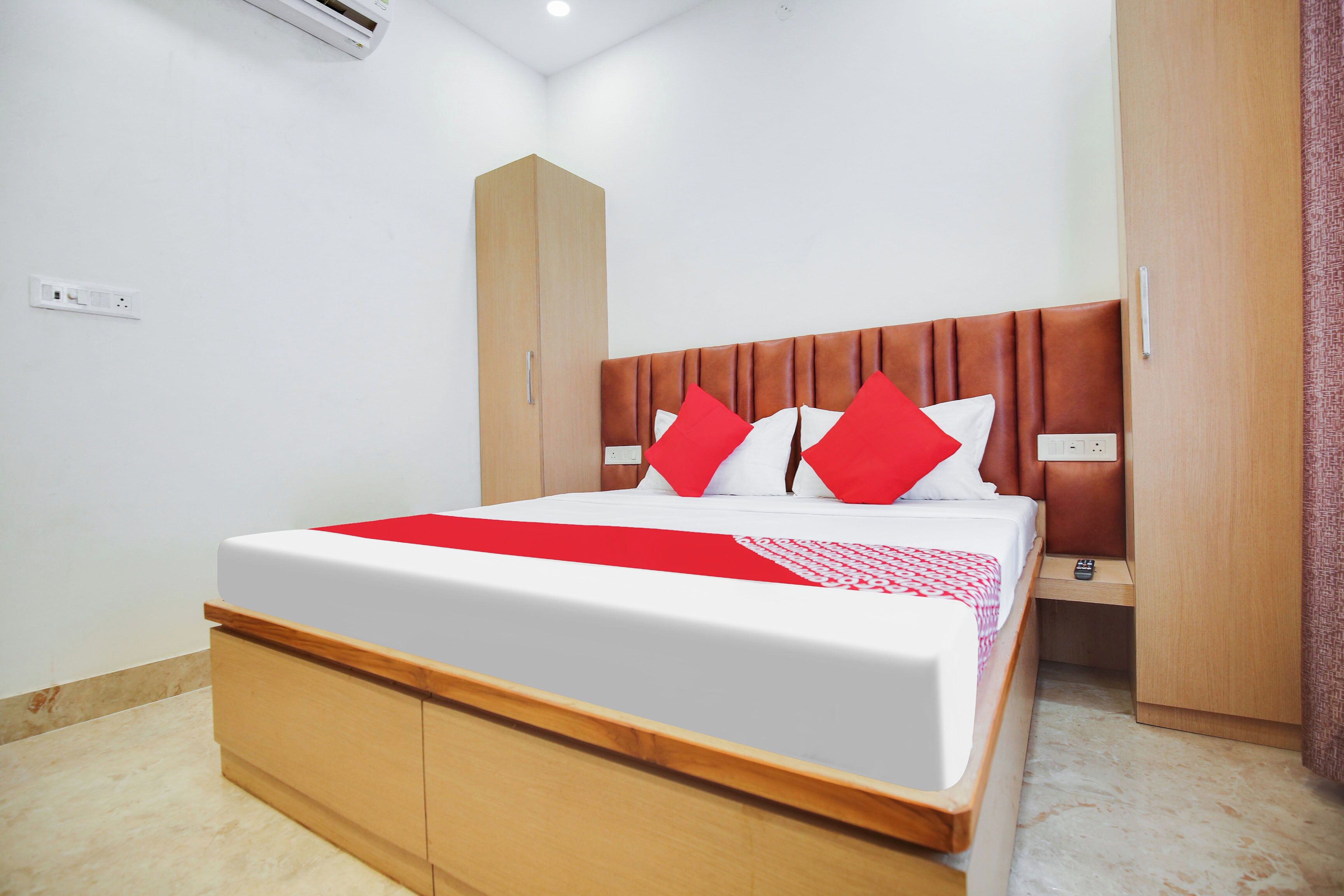 Una habitación de hotel con cama, armario, mesita de noche y toma de corriente.