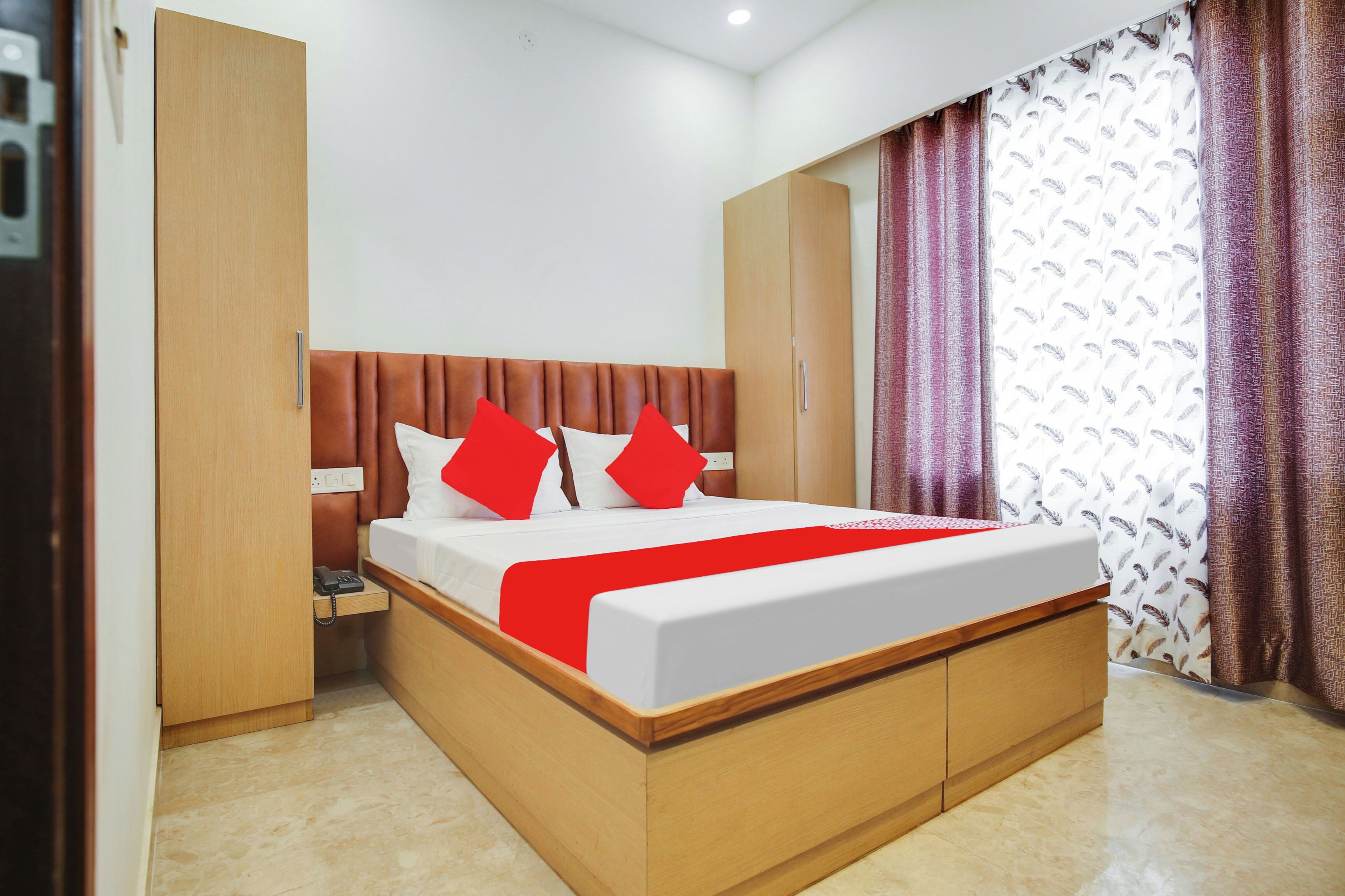 A hotel room with a bed, a wardrobe, a bedside table, and a telephone.