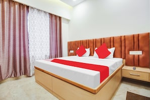 Una habitación de hotel con una cama, una mesita de noche, un control remoto y un enchufe.