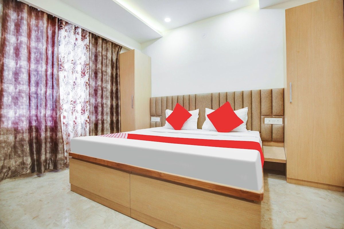 Una habitación de hotel con cama, cortinas, armario y mesita de noche.