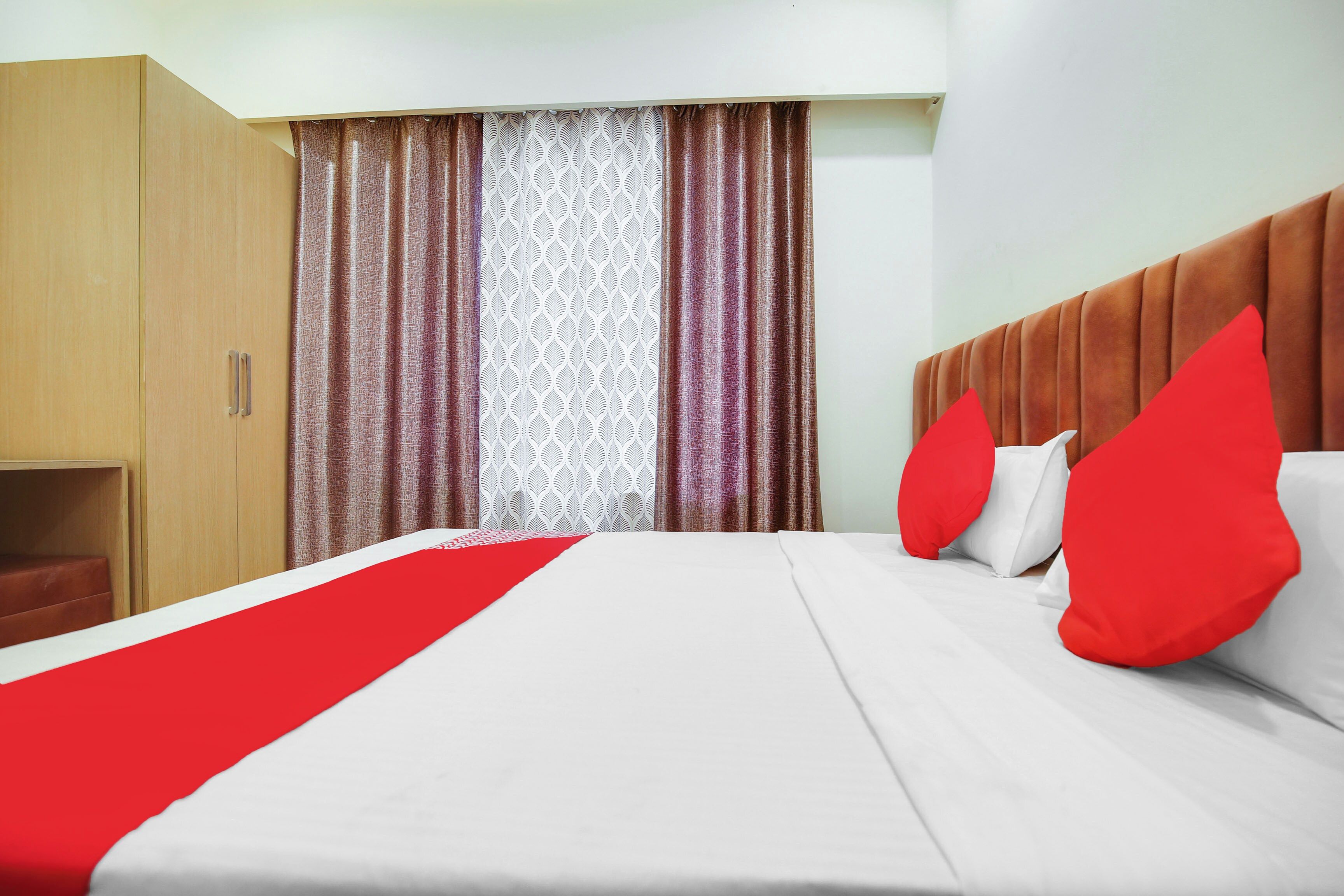 A hotel room with a bed, a wardrobe, and curtains.