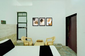 A room with a bed, two chairs, a wall-mounted power outlet, and three framed artworks. - Hotel O CHOUDHARY GUEST HOUSE (Alwar)