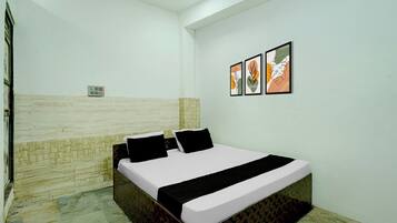 A bedroom with a bed, a wall-mounted power outlet, and two framed artworks.