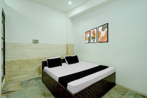 A bedroom with a bed, a wall-mounted power outlet, and two framed artworks. - Hotel O CHOUDHARY GUEST HOUSE (Alwar)