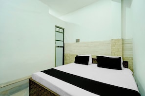 A single-bed room with a plain white wall, a wooden headboard, and a small window. - Hotel O CHOUDHARY GUEST HOUSE (Alwar)