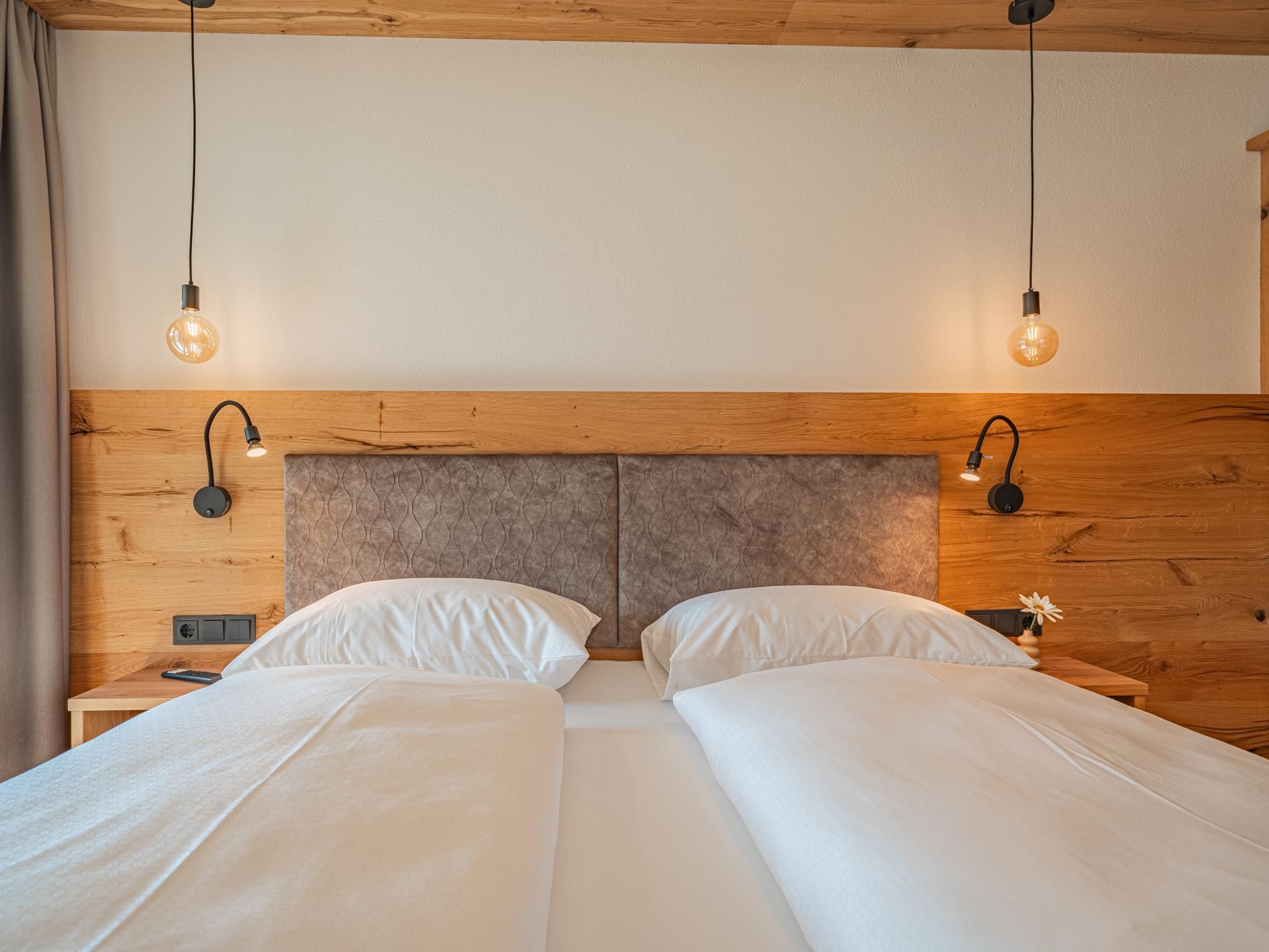 Una cama doble con cabecera de madera y dos lámparas de noche.