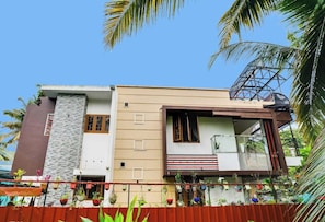 A two-story house with a balcony, a stone facade, and a red fence. - Hotel O Vaishnavam Serviced Villa (Alappuzha)