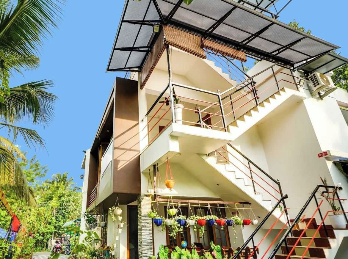 Un edificio de varios pisos con escaleras, plantas exteriores y un panel solar.