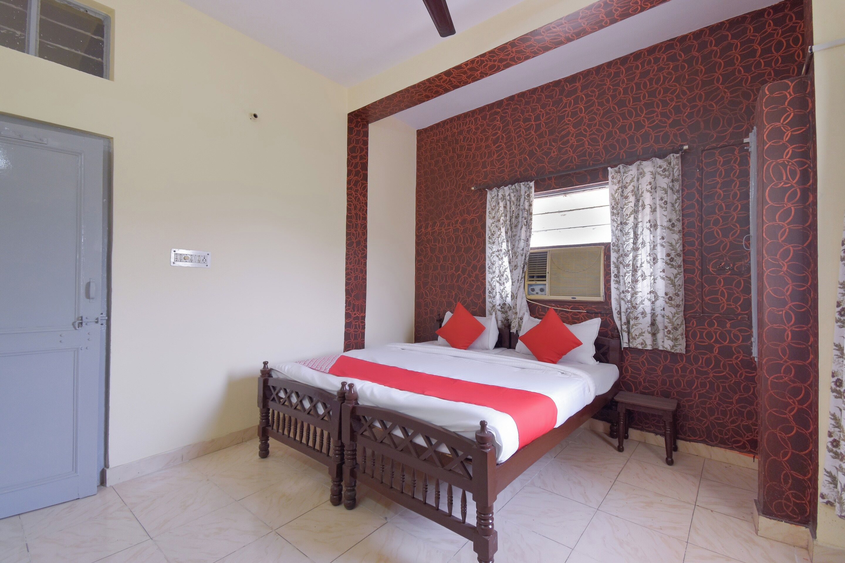 A bedroom with a bed, a bedside table, a mirror, and a door.