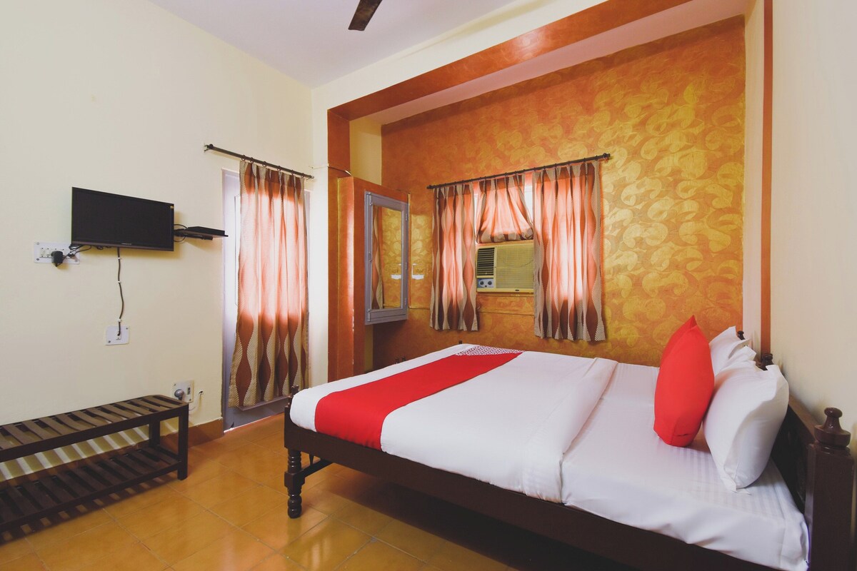 A hotel room with a bed, a television mounted on the wall, and a window with curtains.