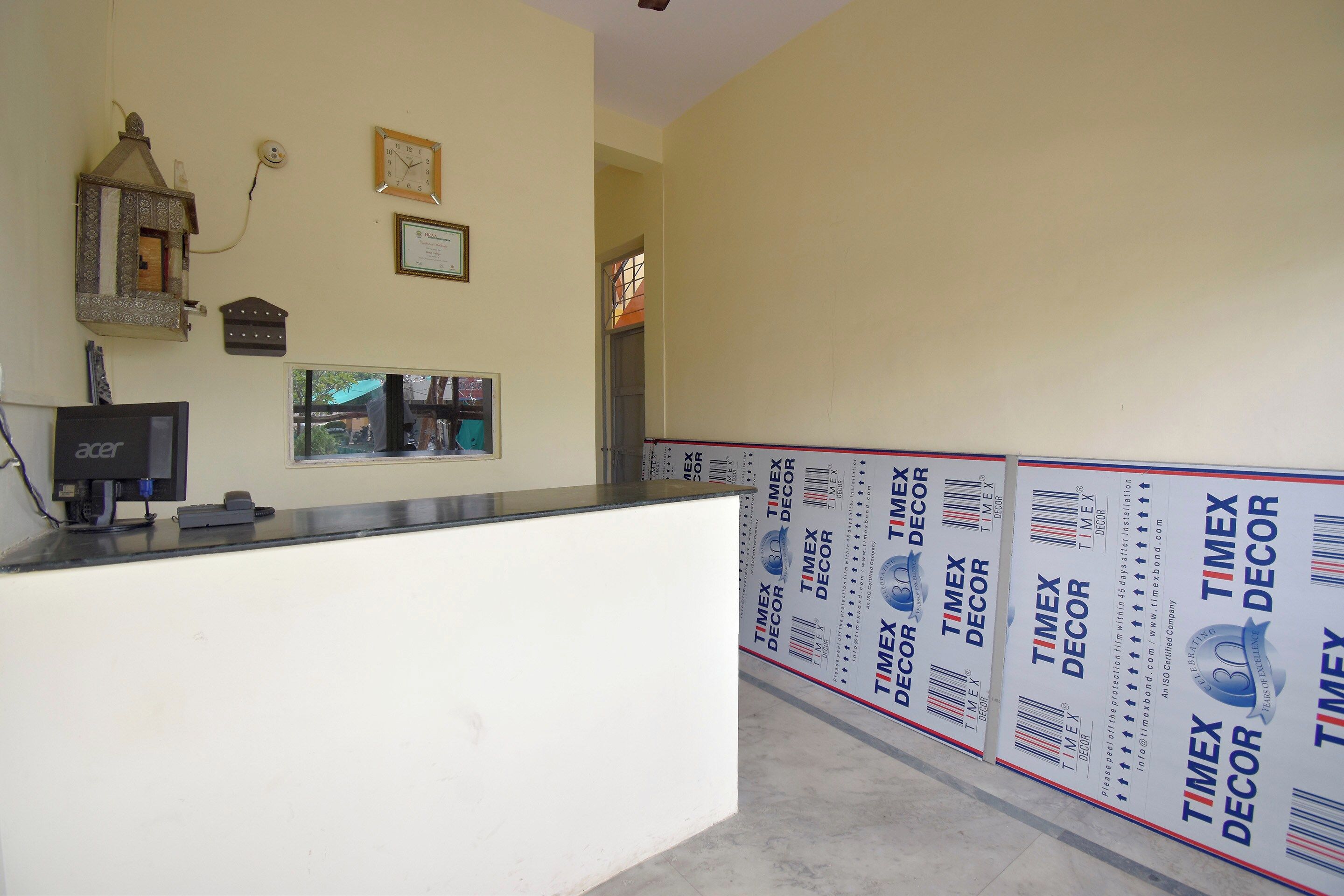 Zona de recepción con mostrador, un reloj y un certificado enmarcado en la pared.