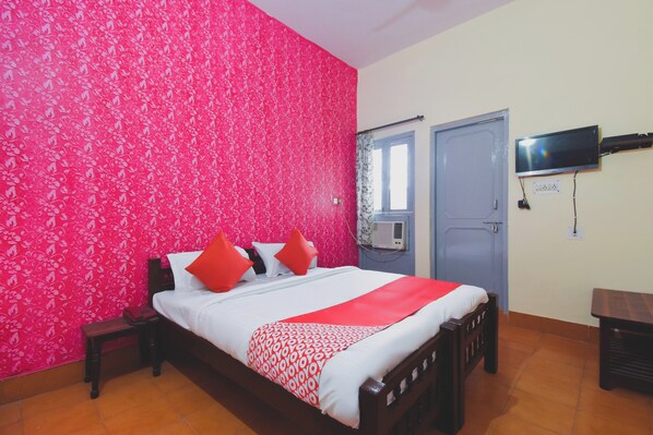 A hotel room with a bed, a television mounted on the wall, and a window with a curtain. - Hotel O Aditya (Alwar)