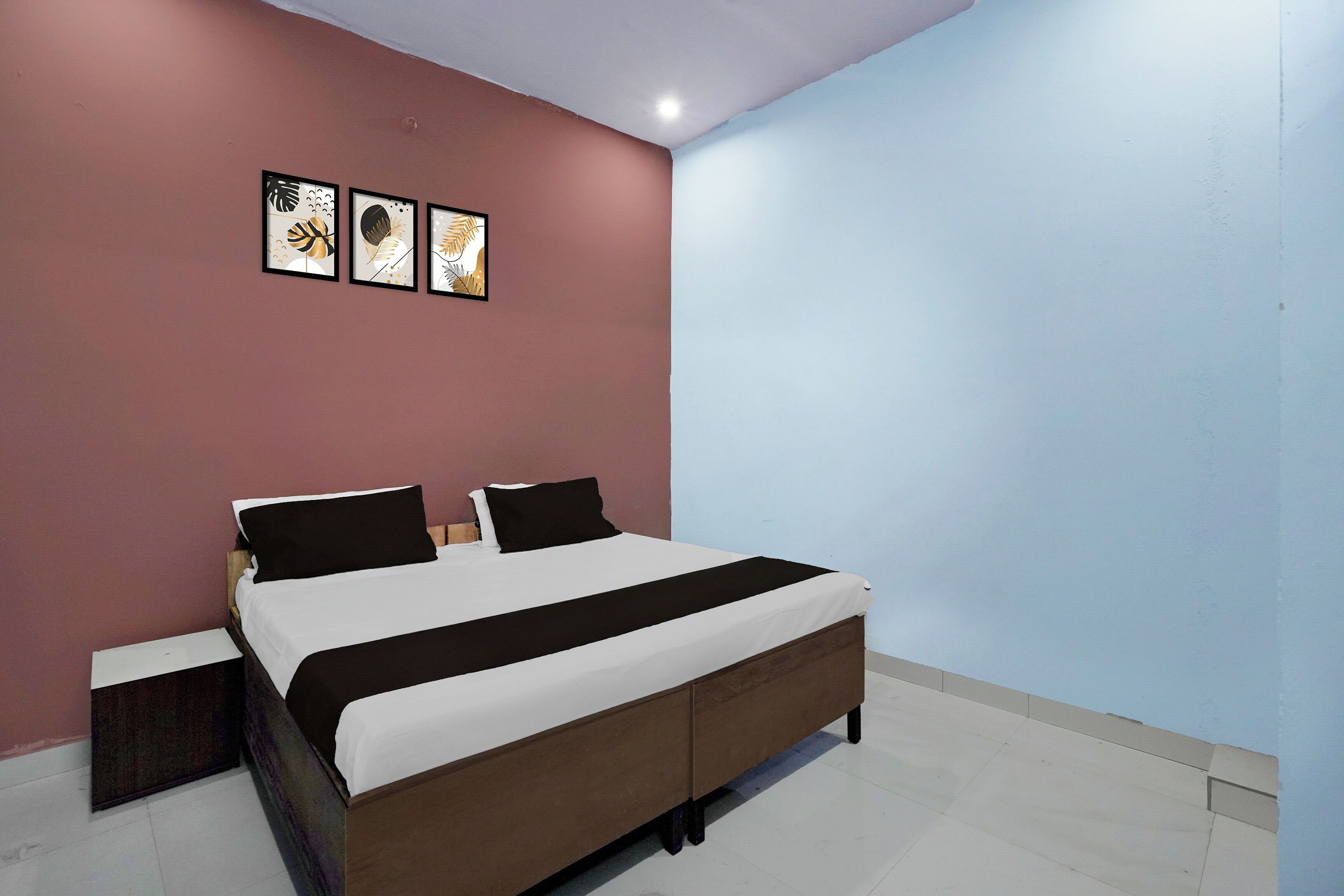 Un dormitorio con una cama, dos mesitas de noche y una pared con tres obras de arte enmarcadas.