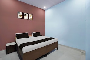 Un dormitorio con una cama, dos mesitas de noche y una pared con tres obras de arte enmarcadas.
