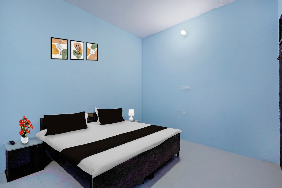 Un dormitorio con cama, mesitas de noche, lámpara y tres cuadros en la pared.