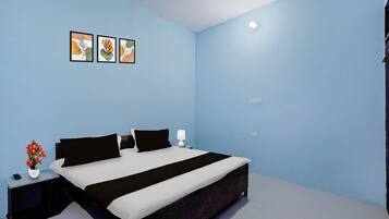 Un dormitorio con cama, mesitas de noche, lámpara y tres cuadros en la pared.