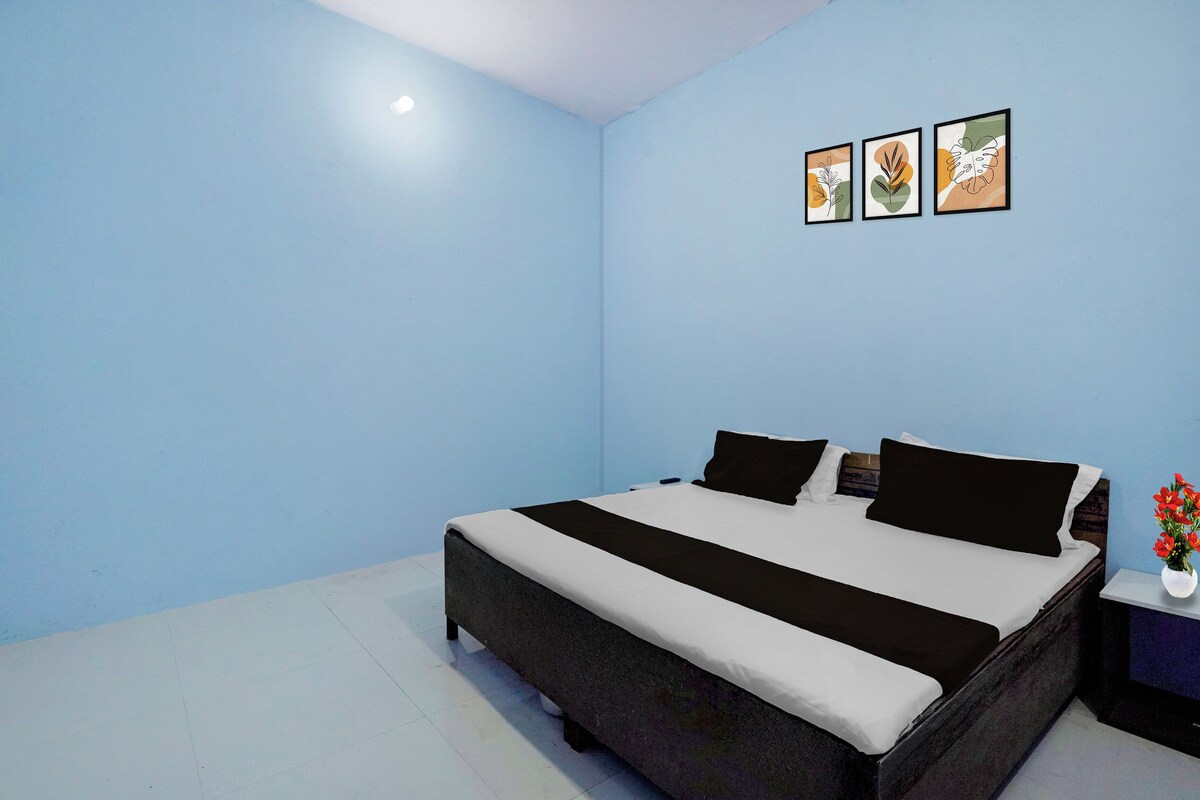 A bedroom with a bed, a nightstand, and a wall-mounted shelf.