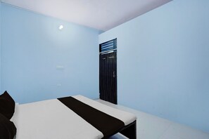 Una habitació amb llit, finestra i porta.