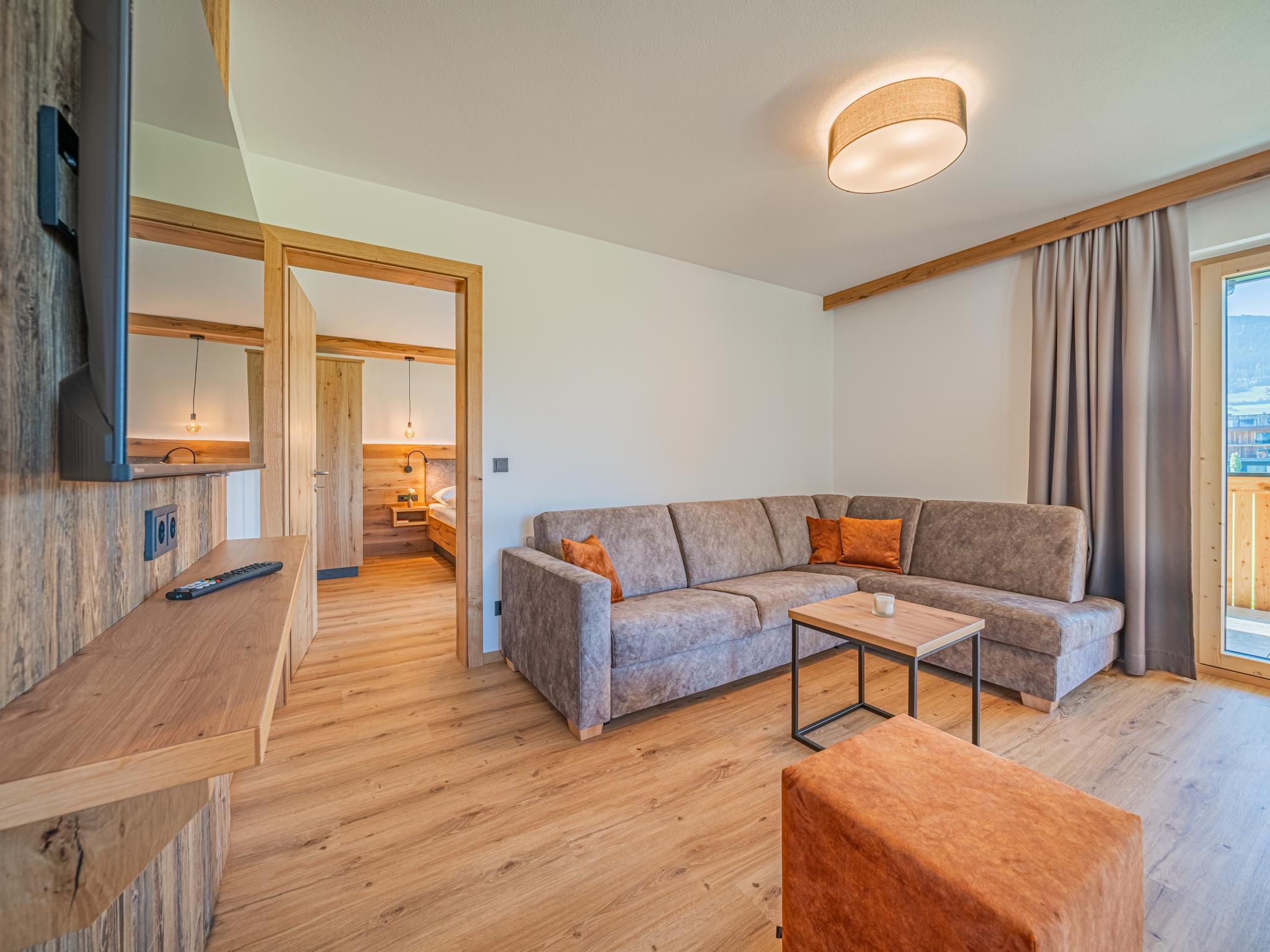 Ein modernes Wohnzimmer mit einer Eckcouch, einem Couchtisch und einem an einer Holzwand montierten Fernseher.