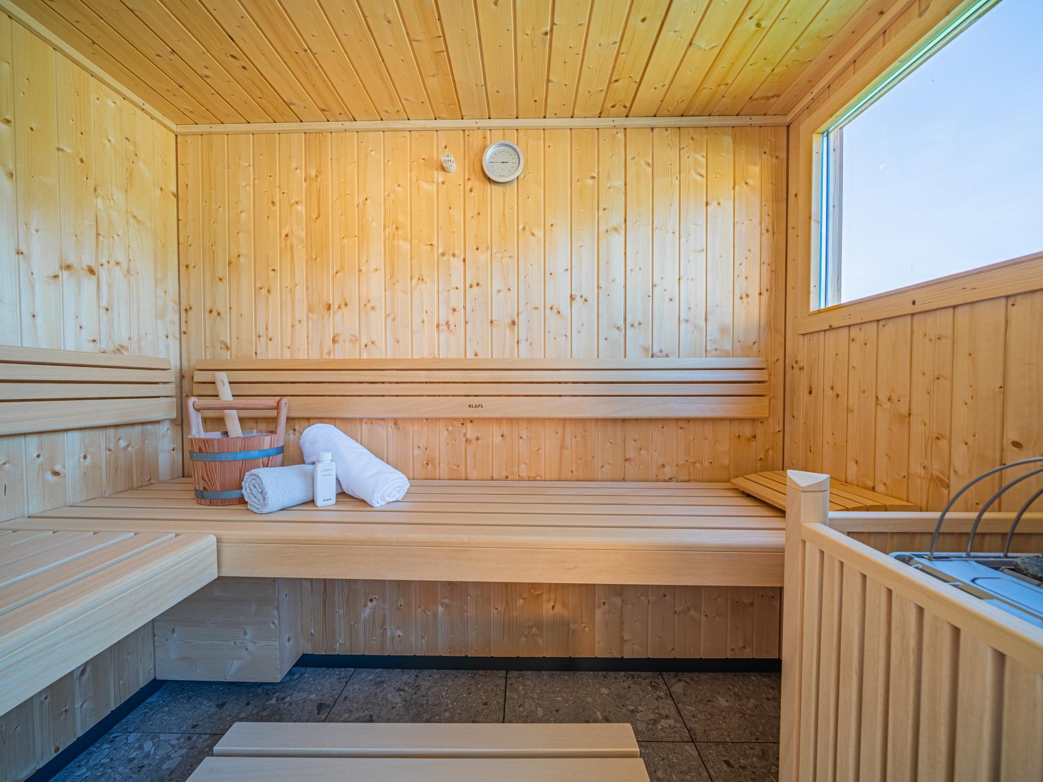 A sauna with wooden benches, a towel, and a bottle, likely containing a product for use in the sauna.