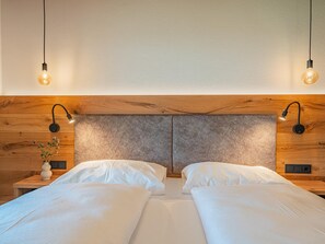 Un llit doble amb dues taules de nit, cadascuna amb una làmpada, en una habitació amb panells de fusta i un capçal de llit amb relleu.