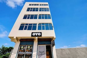 Un edifici de diversos pisos amb un cartell prominent d''OYO'' a la planta baixa.