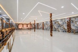 Un vestíbulo amplio con piso de mármol, una recepción y un decorado llamativo.