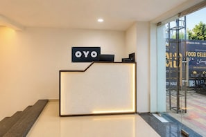 Ein Empfangsschalter mit einem Schild, auf dem 'OYO' steht, und eine Glastür, die nach draußen führt.