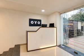 Una recepción con un cartel que dice 'OYO' y una puerta de cristal que da al exterior.