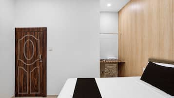 A bedroom with a wooden door, a bed with a black headboard, and a wooden wall panel.