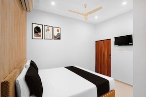Ein Schlafzimmer mit einem Bett, einem Deckenventilator, einem Fernseher und drei gerahmten Kunstwerken an der Wand.